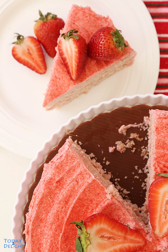 Showing one-fourth of the cake on a stand with a slice of strawberry cake already served.