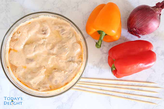 Marinated pork in yogurt marinade to make kebabs with 4 skewers. 1 whole yellow and red bell peppers and 1 large red onion.