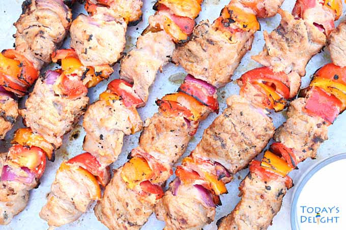 Skewered grilled pork kabobs with vegetables on a tray.