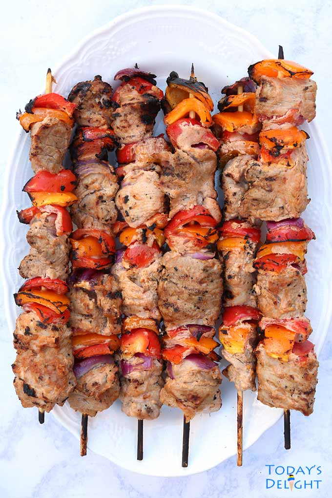 Six grilled pork shish kebabs in a platter.