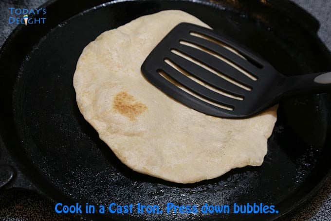 Tortilla cooked in cast iron and pressed with a kitchen utensil.