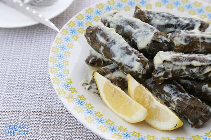 Plated dolmades with lemon wedges.