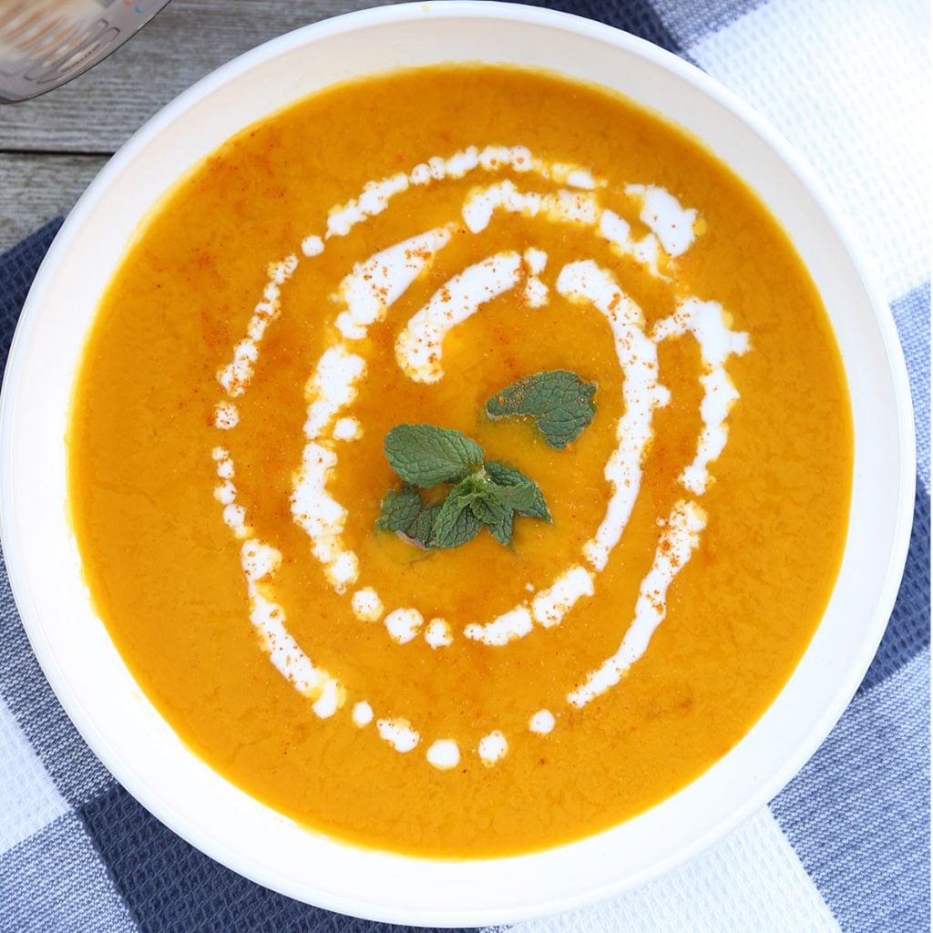 Kabocha Squash Soup with coconut milk and mint leaves at the center.