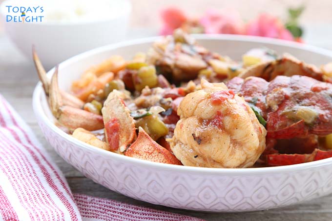Crabs, lobster tail and shrimp gumbo on serving bowl.