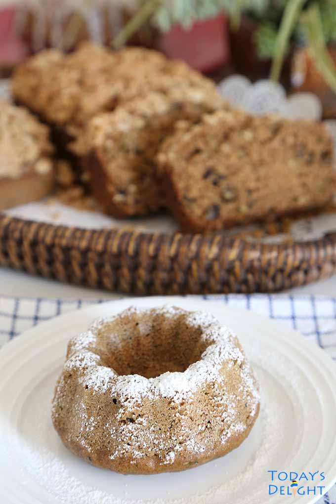 Zucchini bread bundt shaped on a plate with powdered sugar dusting.