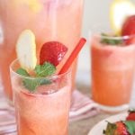2 glasses of homemade Strawberry Lemonade Drink garnished with strawberry, lemon and mint leaves.