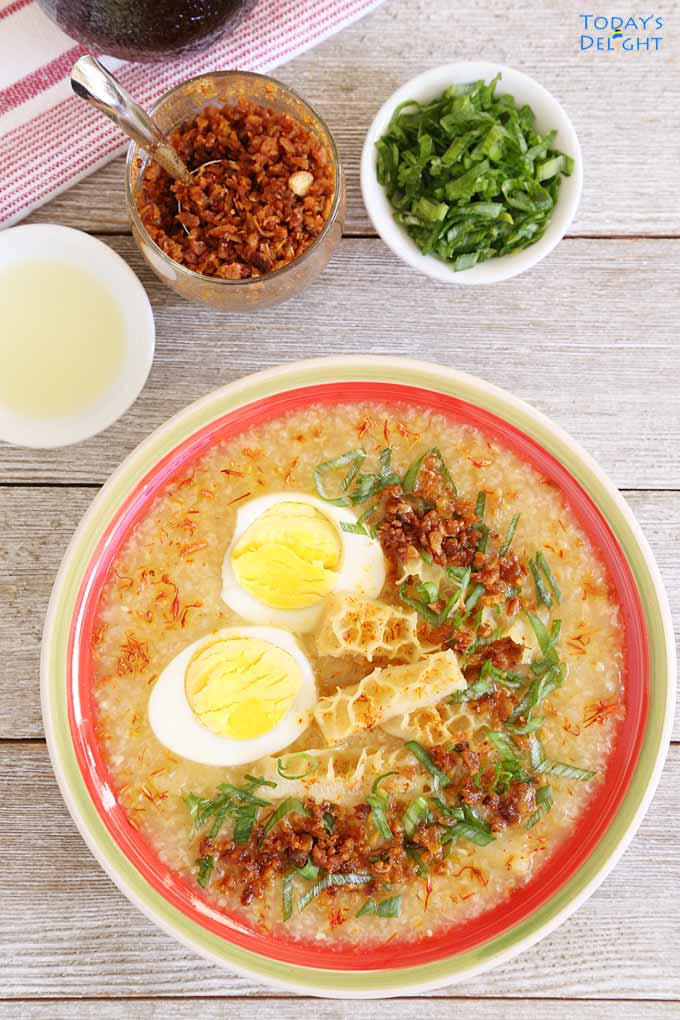A bowls of Goto is a Filipino congee or rice porridge with tripe and hardboiled egg, and a side of lemon juiice, fish sauce and toasted garlic .