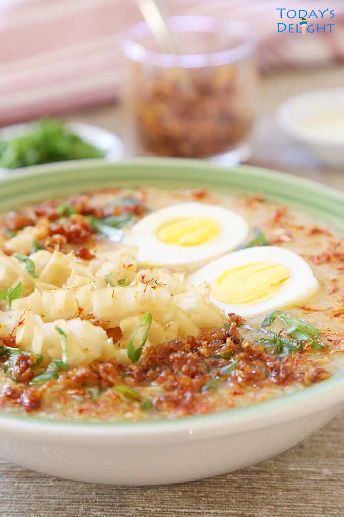 A bowl of hot Filipino rice porridge with tripe, toasted garlic, hardboiled egg sprinkled with green onions.