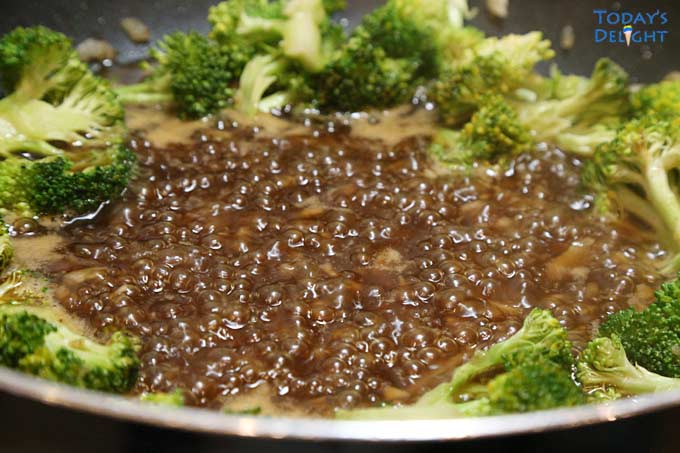 Simmering sauce and broccoli in pan.