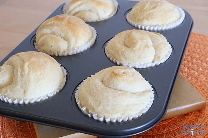 Six baked sweet bread rolls in baking pan.