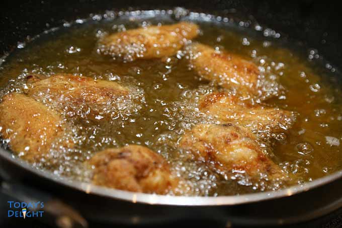 Deep frying wings in hot oil.