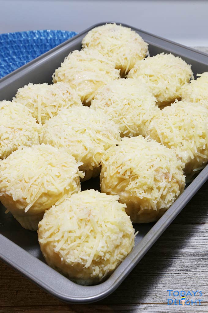 A baking pan of 12 ensaymada, a Filipino brioche bread topped with butter, sugar, and grated cheese.