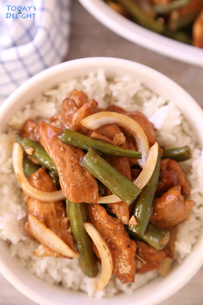 A bowl of rice with chicken and green bean stir fry.