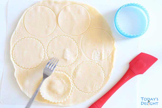 Rolled up dough cut with cookie cutter to make mini quiche shells.
