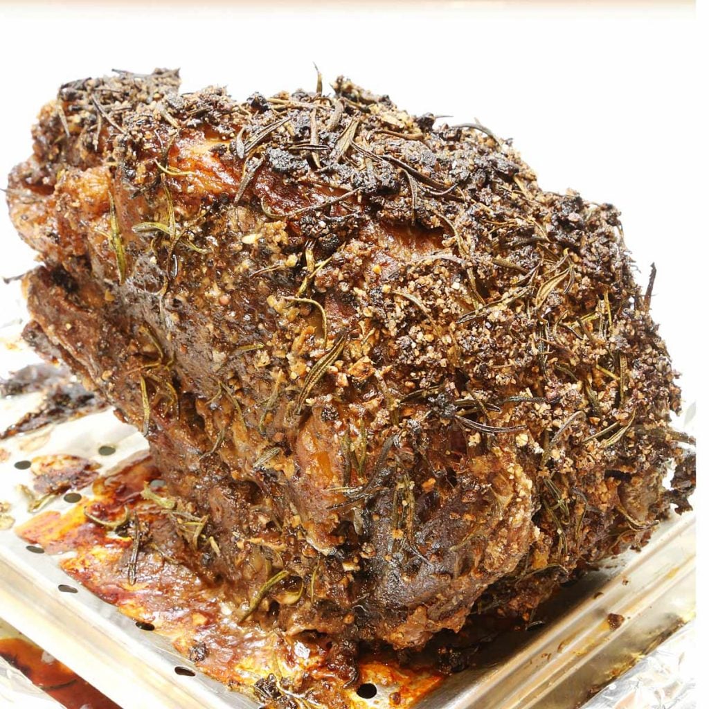 Slow roasted prime rib with herbs on tray rack.