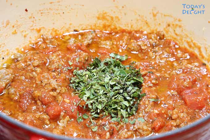 Fresh chopped oregano and basil added in the meat and tomato sauce mixture.