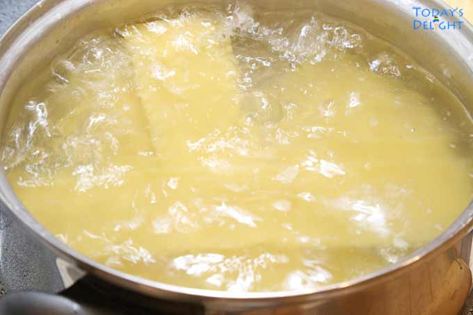 Boiling the dry lasagna noodles in a pot.