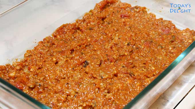 Lasagna meat sauce spread at the bottom of casserole baking pan.