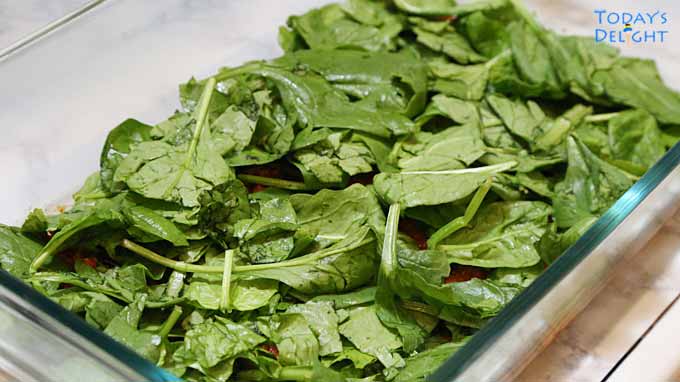 Fresh spinach is added on top of meat sauce in the casserole pan.