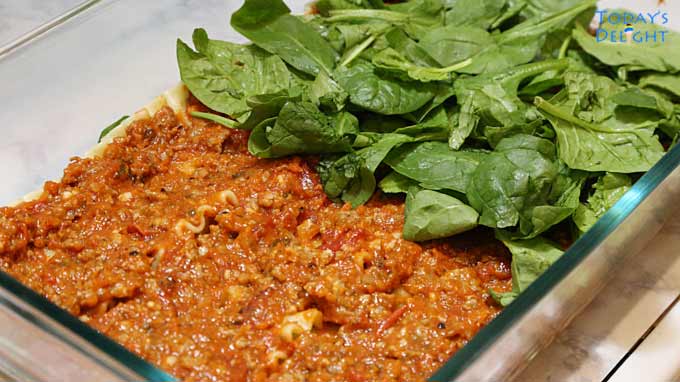 Fresh spinach is layered on top of the meat sauce.
