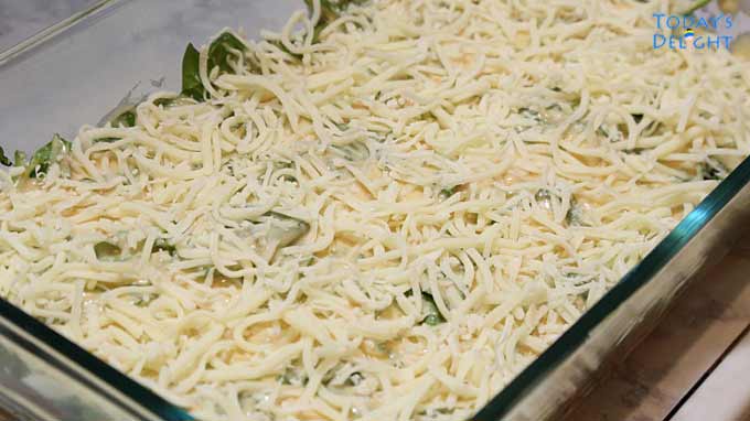 Unbaked lasagna topped with grated mozzarella cheese in a casserole pan.