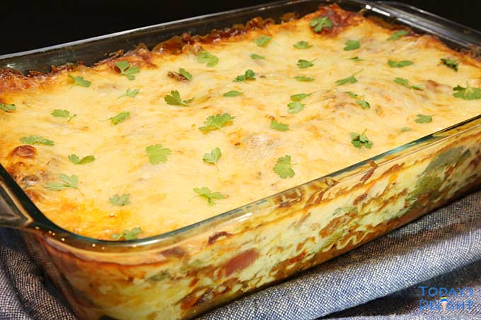 Baked spinach and beef lasagna garnished with fresh parsley leaves in a casserole baking pan.