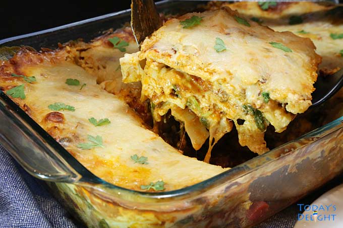 A slice of baked spinach and beef lasagna taken from the casserole pan.