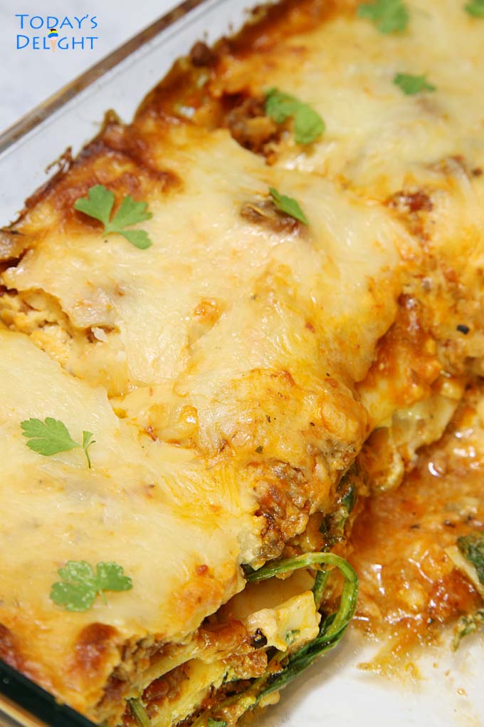 Three slices of baked lasagna garnished with fresh parsley leaves in the casserole pan.