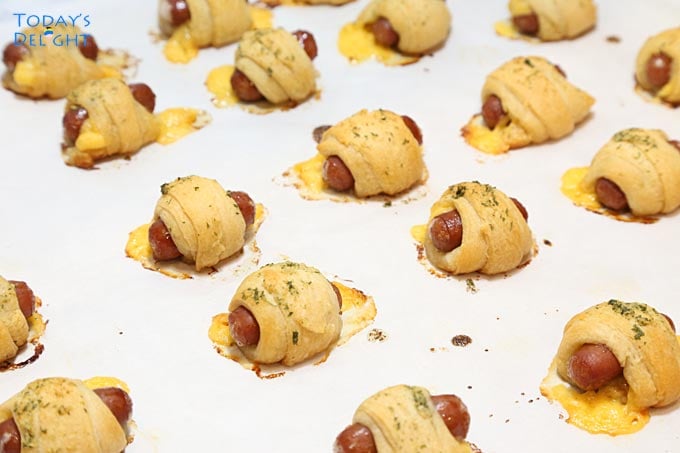 Baked Crescent Roll Pigs in a Blanket with Garlic Herb Butter in cookie sheet.