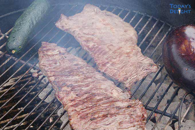 Flank steak on grill with zucchini and eggplant.