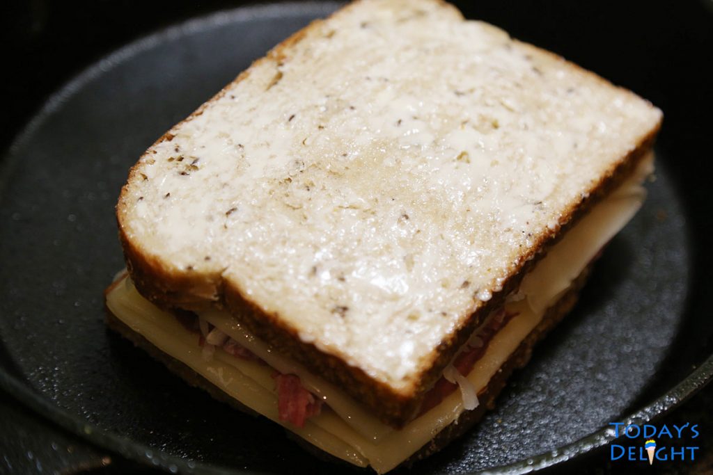 Whole reuben sandwich with garlic aioli on cast iron.