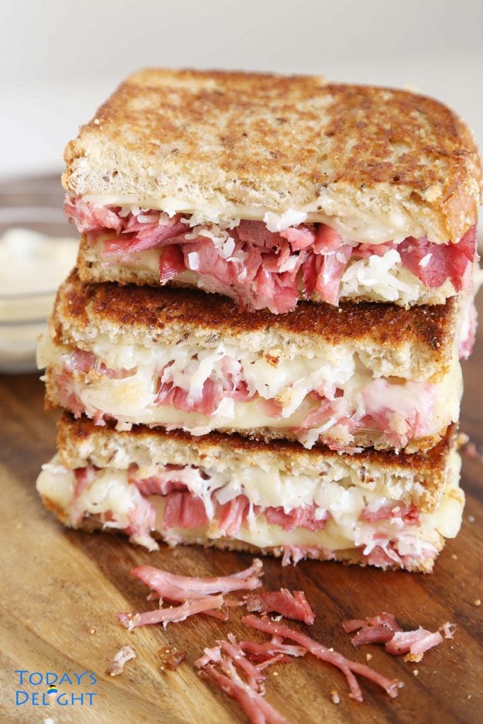 3 piles of half reuben sandwich with garlic aioli.