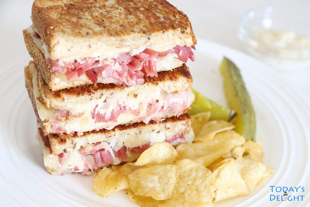Reuben Sandwich with Garlic Aioli and side of chips and dill spears.