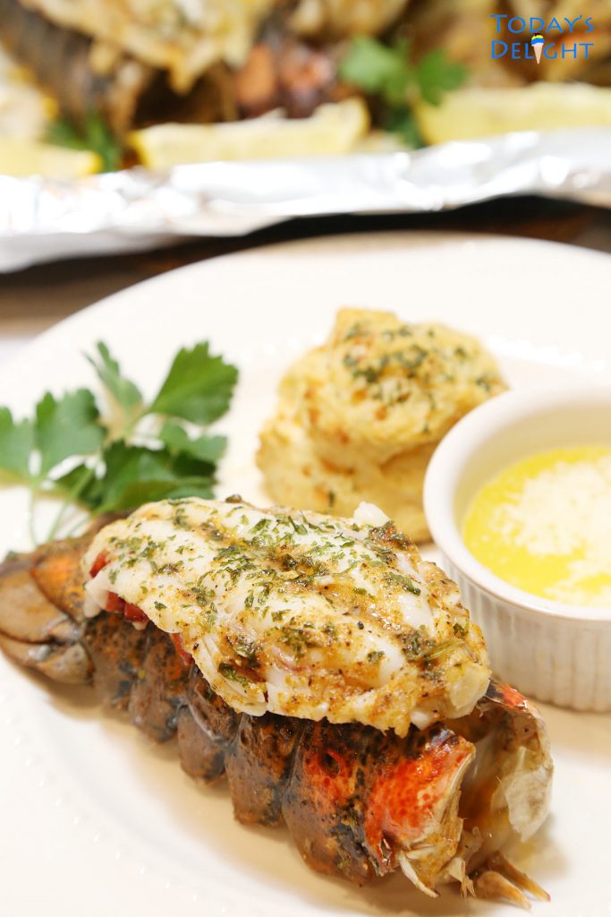 Broiled lobster on a plate with biscuit and melted butter.