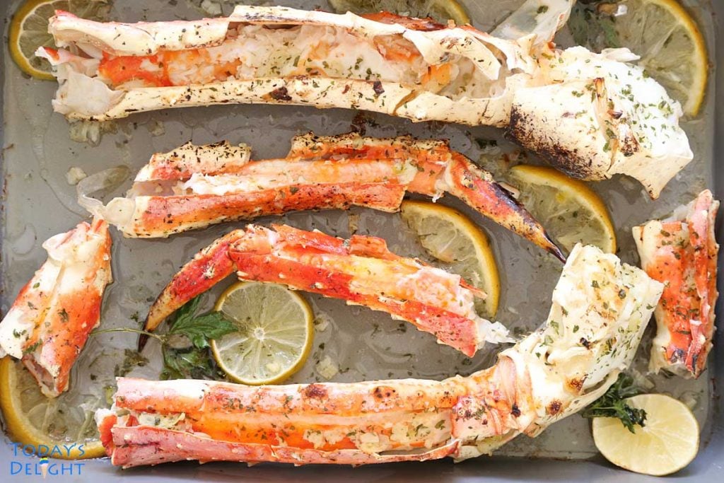 2 big baked crab legs in garlic butter and lemon wedges.