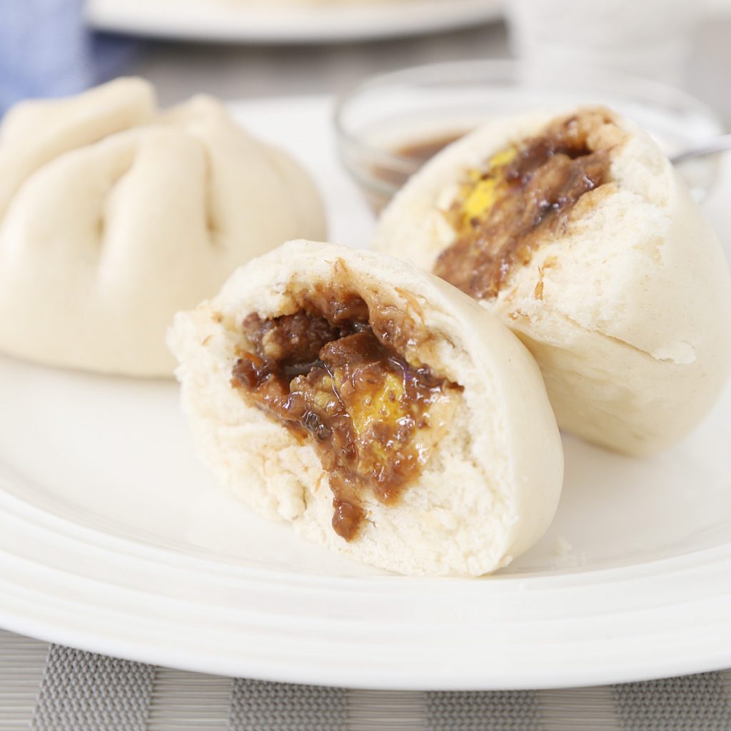 2 Pork siopao asado with egg and sauce.