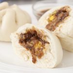 2 Siopao Asado (Filipino steamed pork buns) with sauce.