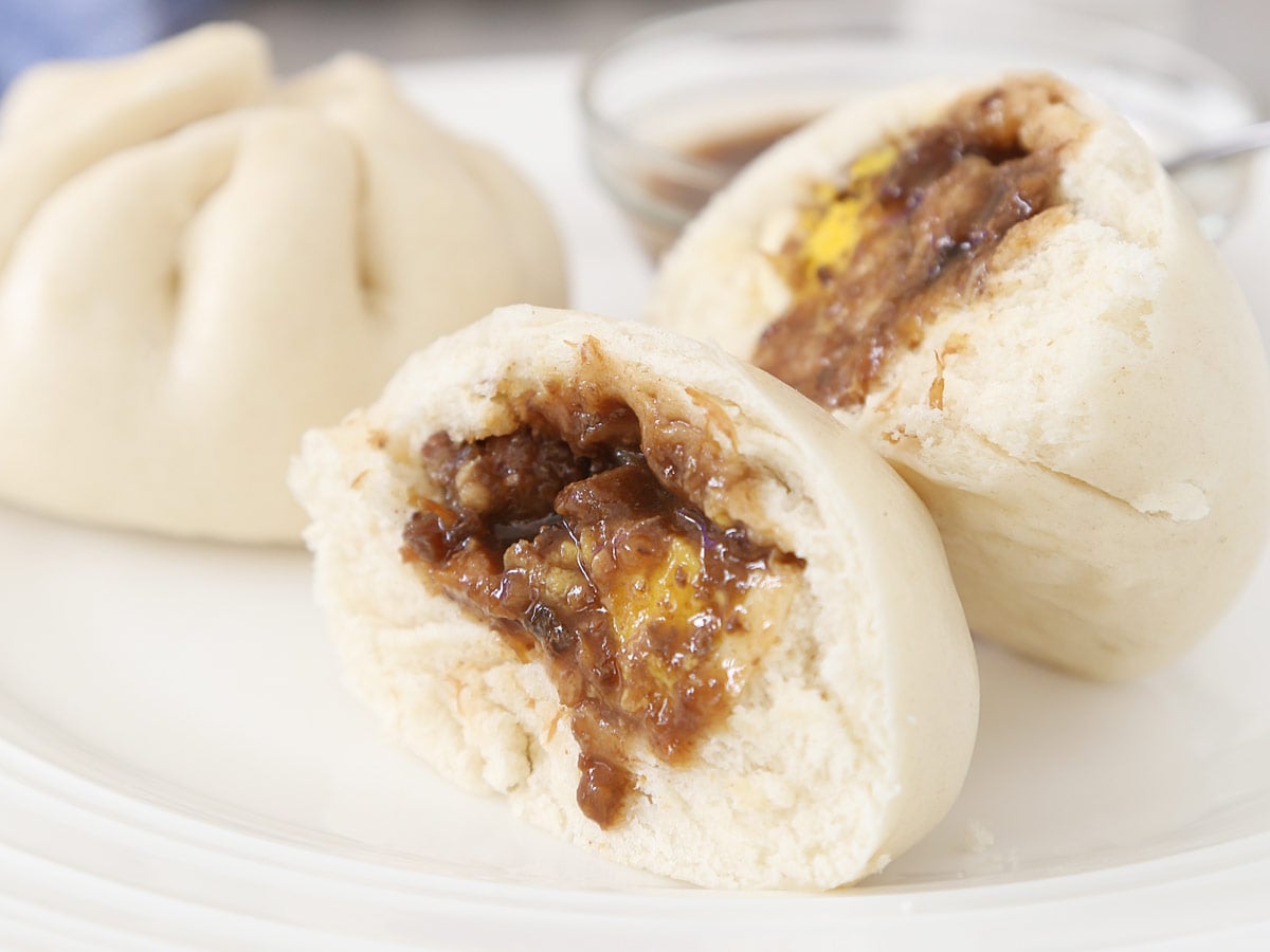 2 Siopao Asado (Filipino steamed pork buns) with sauce.