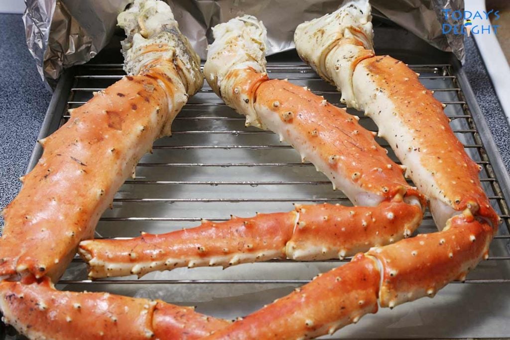 3 King crab legs on a rack in a big tray.