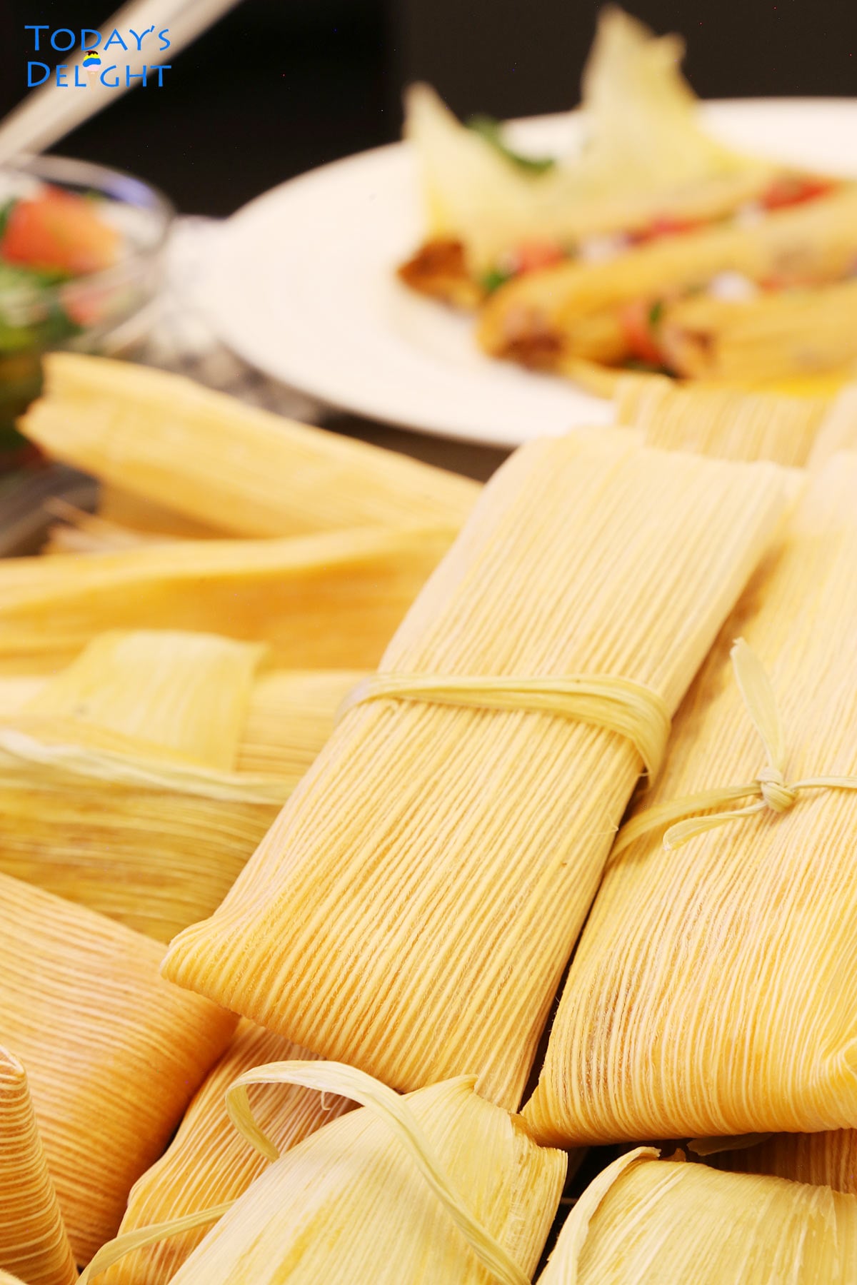 Tray of Mexican tamales, a plate of unwrapped tamales and pico de gallo.