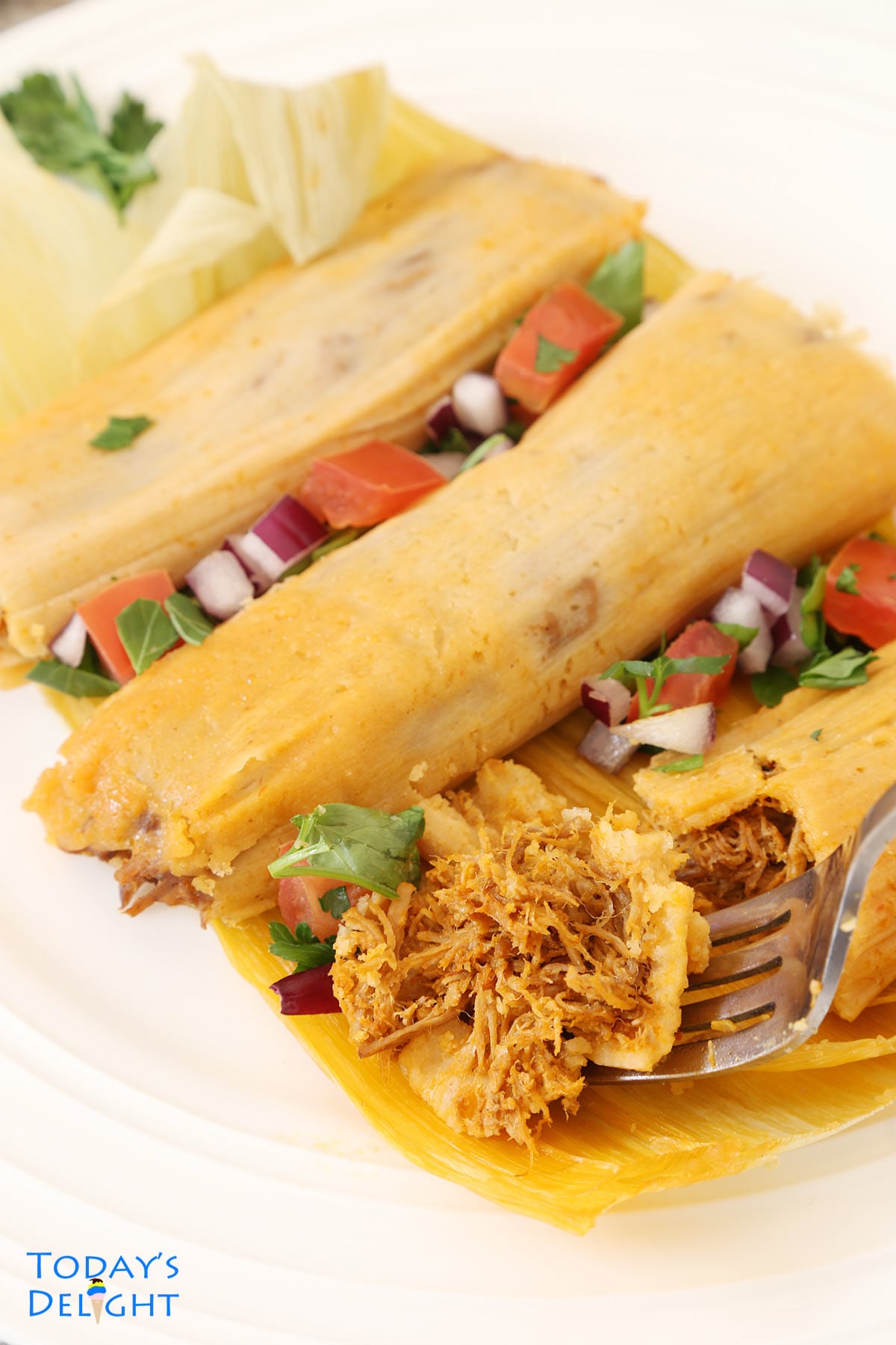 A bite of tamales in one of the 3 unwrapped tamales.