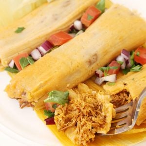 Fork with a bite of one of 3 tamales.