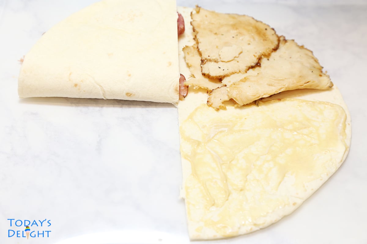 Lower left side of tortilla folded upward toward ham.