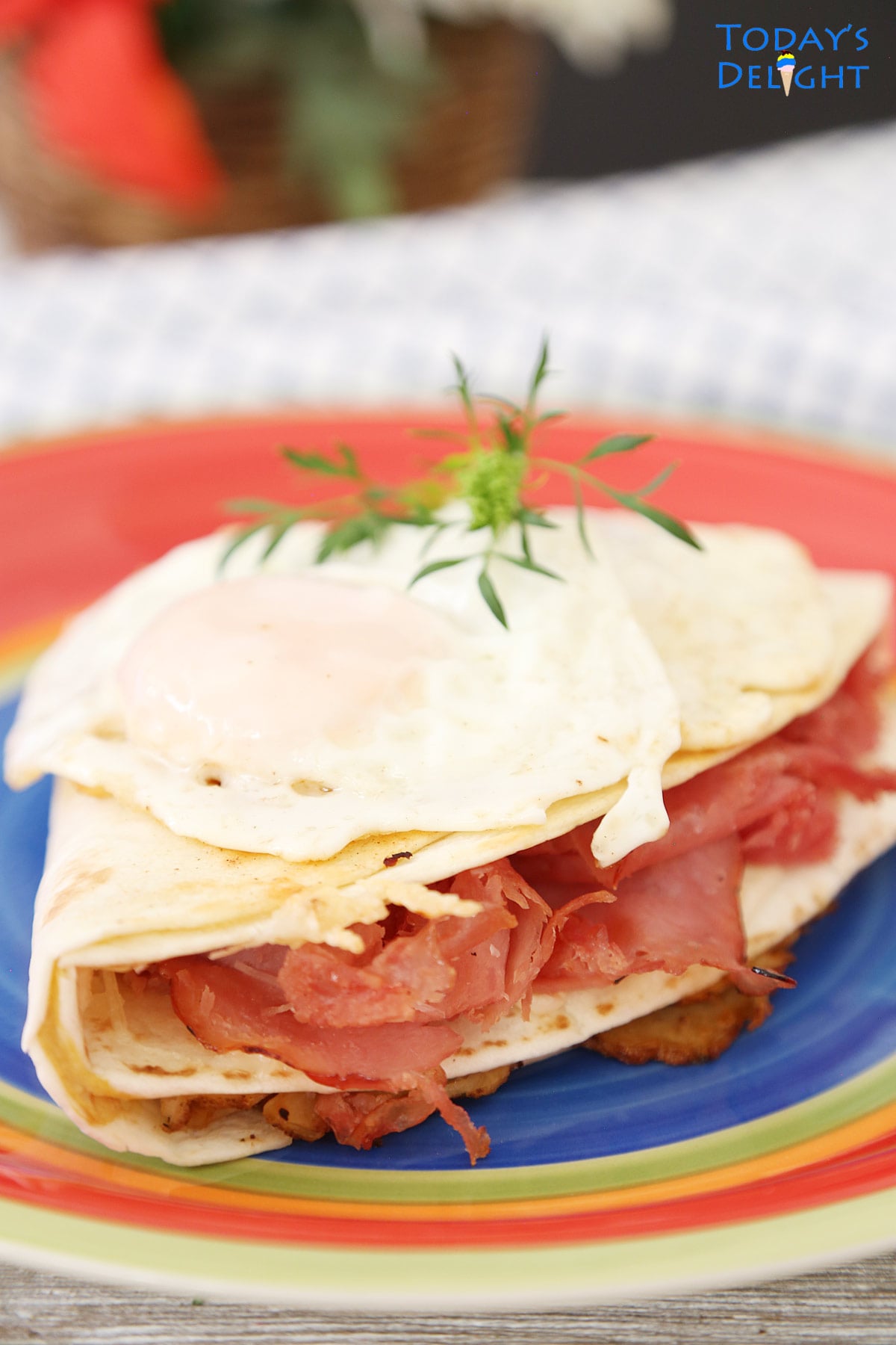 A serving of Monte Cristo Sandwich in Tortilla Wrap with turkey, ham and cheese and topped with 2 over easy eggs.