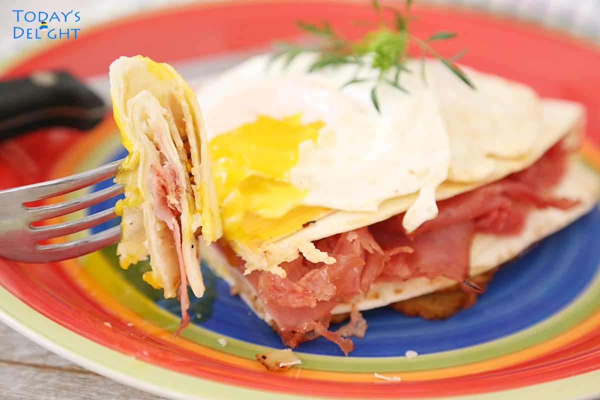 A slice of the Crispy Monte Cristo Sandwich in Tortilla Wrap in a fork with runny egg yolk.