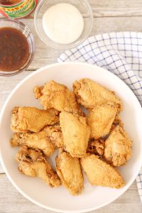 Crispy Patis Fried Chicken Wings in a plate with a side of blue cheese dressing, sweet and spicy sauce and ketchup.