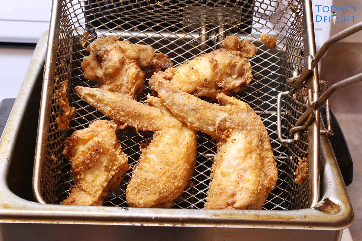 Fried 2 Whole chicken wings, 2 drumettes and 1 flap wing in a basket in deep fryer.