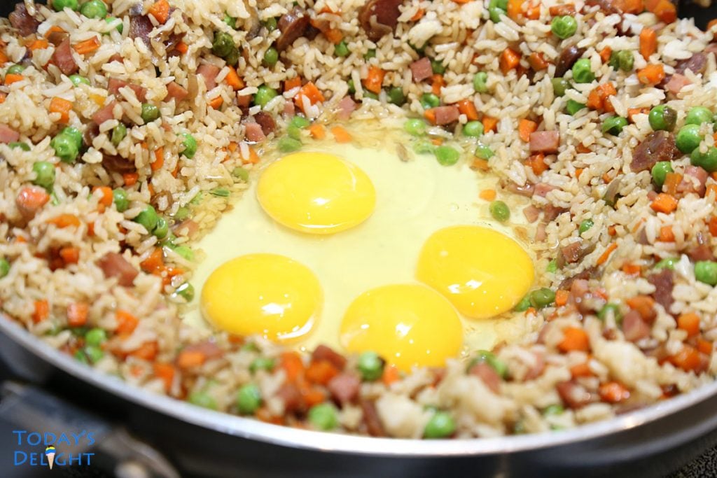 Fried rice pushed to the side making a well with whole raw eggs at the center.