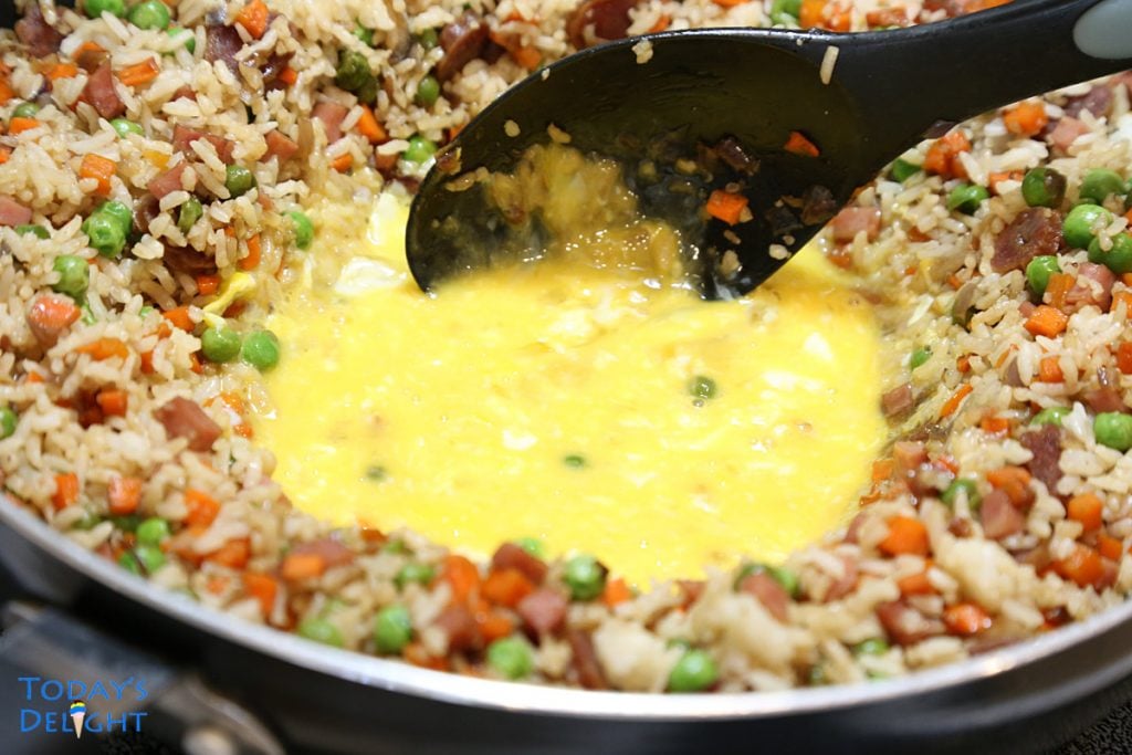 Fried rice pushed to the sides of skillet making a well to scramble the eggs at the center.