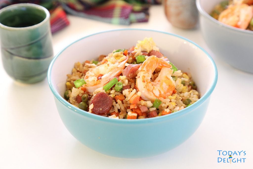 A serving of shrimp fried rice in a bowl with tea.